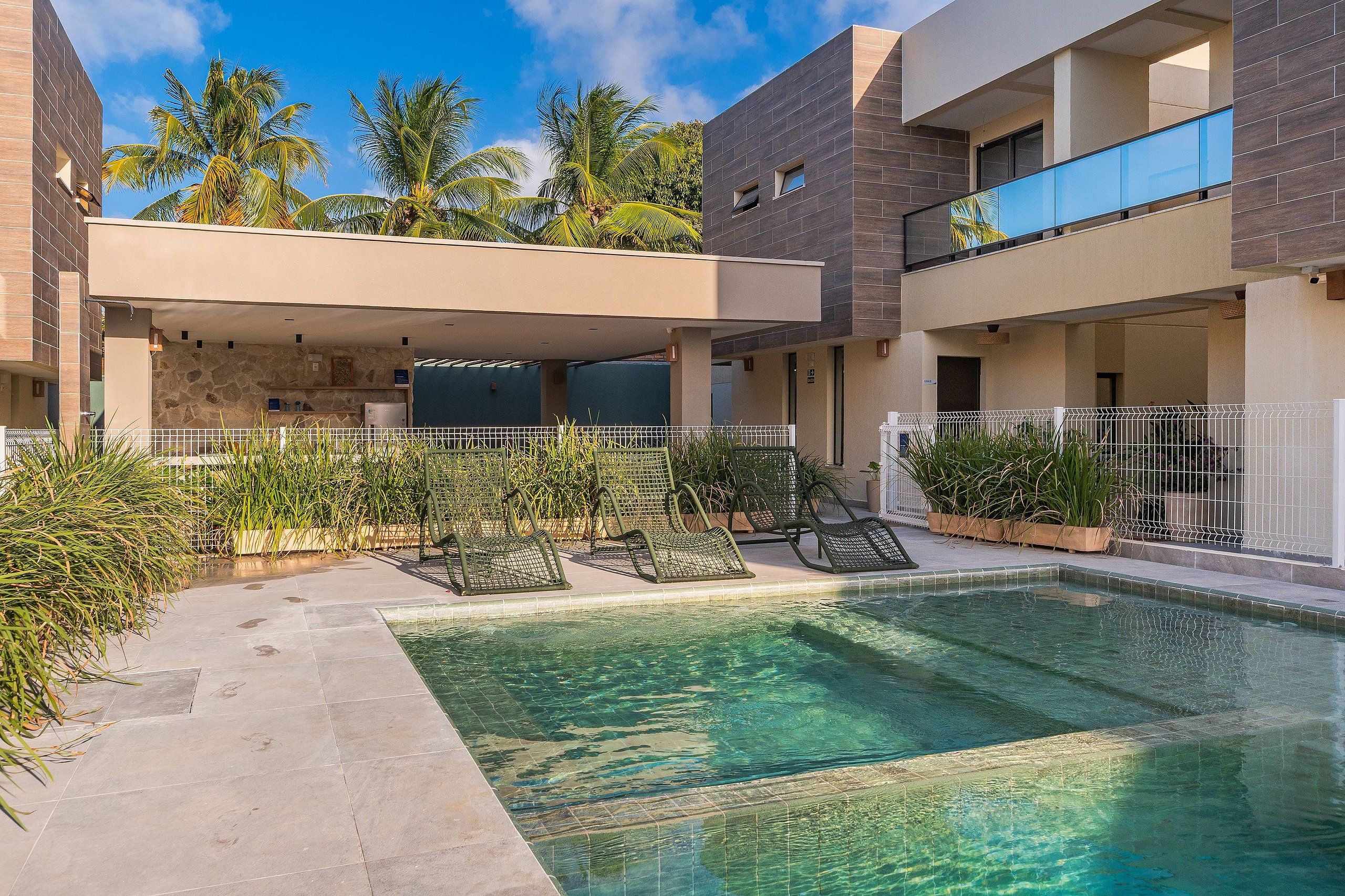 A modern outdoor pool area with lounge chairs and a covered seating area.
