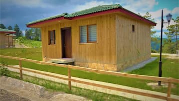 A wooden cabin with a red roof, a door, and a window.