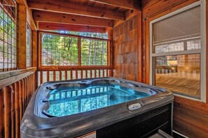 A hot tub in a wooden cabin with a window view of trees. - New Luxury Lodge • Private Pool • Hot Tub • Game Room • Sleeps 18 (Sevierville)