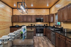 Une cuisine moderne avec des murs en bois, des appareils électroménagers en acier inoxydable et un îlot central agrémenté de présentoirs à verres.