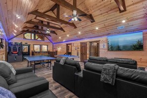 A wooden interior with a ping pong table, sofas, and a basketball hoop. - New Luxury Lodge • Private Pool • Hot Tub • Game Room • Sleeps 18 (Sevierville)