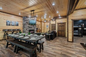 A wooden interior with a dining area, fireplace, and seating. - New Luxury Lodge • Private Pool • Hot Tub • Game Room • Sleeps 18 (Sevierville)