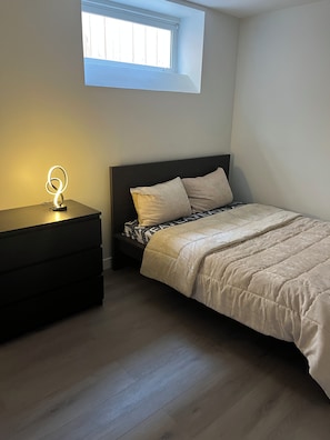 Ein Schlafzimmer mit einem Bett, einem Nachttisch und einem kleinen Fenster.
