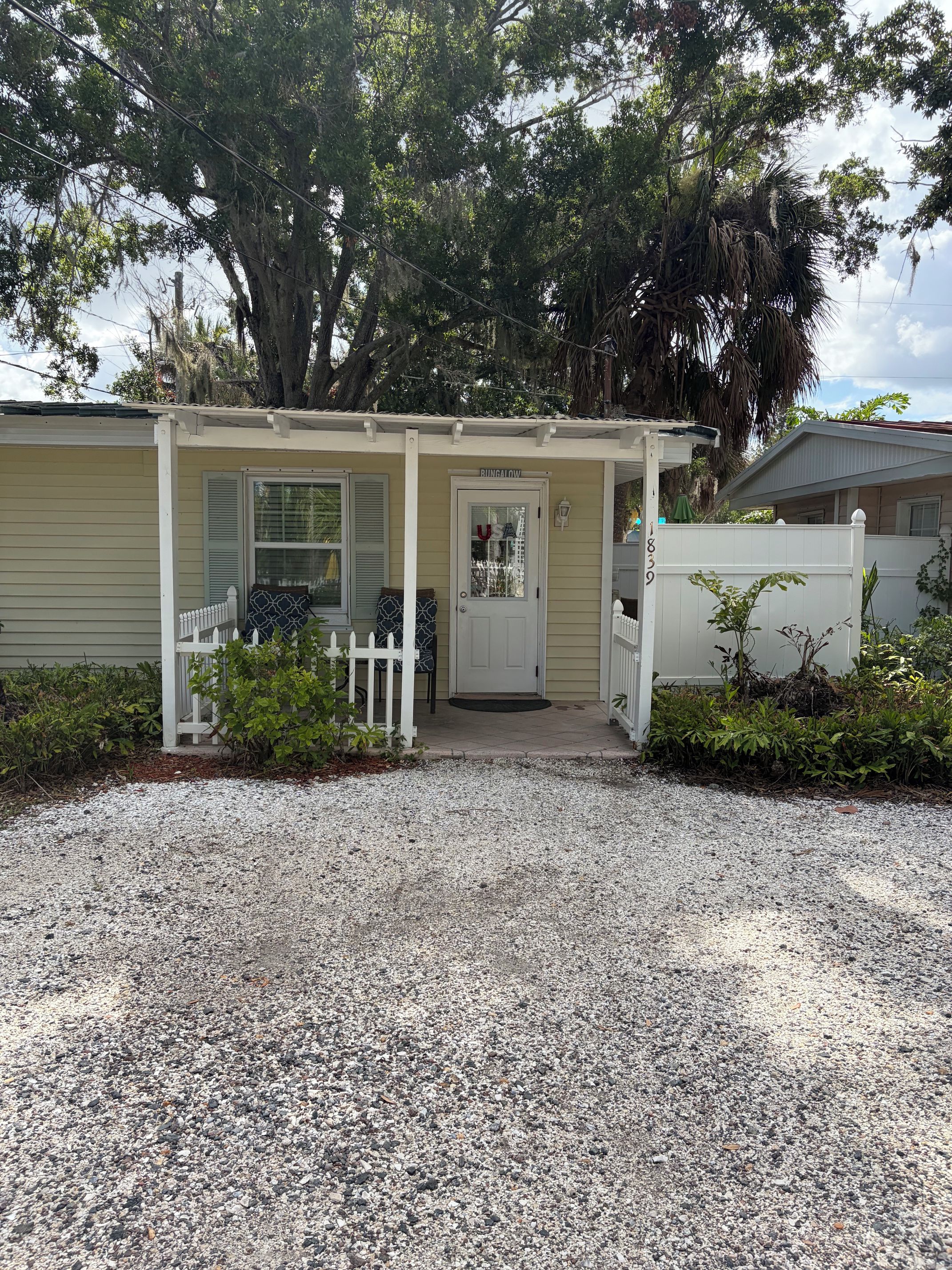 A bungalow with a covered porch, a front door, and a white picket fence.