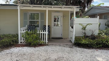 A bungalow with a covered porch, a front door, and a white picket fence.