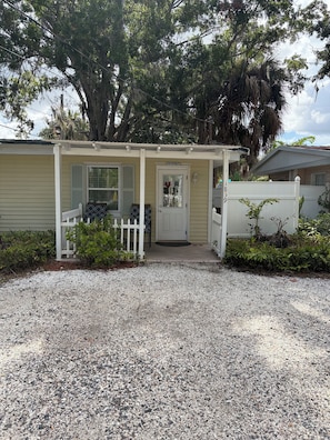A bungalow with a covered porch, a front door, and a white picket fence.