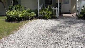 Een bungalow met een grindpad, een witte veranda en een voordeur met de tekst 'BUNGALOW'.