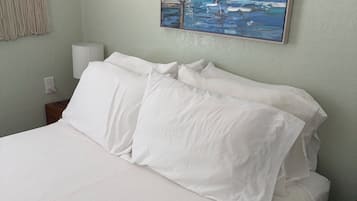 Een net opgemaakt bed met witte lakens in een kamer met een lichtgroene wand.