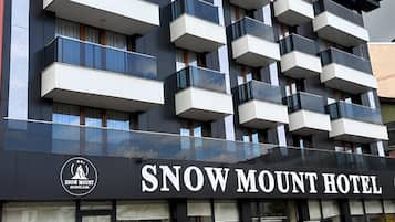 A multi-story hotel with balconies, a prominent signage for 'Snow Mount Hotel,' and a logo indicating it is a hotel and spa.