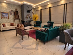 Ein modernes Wohnzimmer mit Kamin, grünen Sofas, einem Couchtisch und einem Teppich.