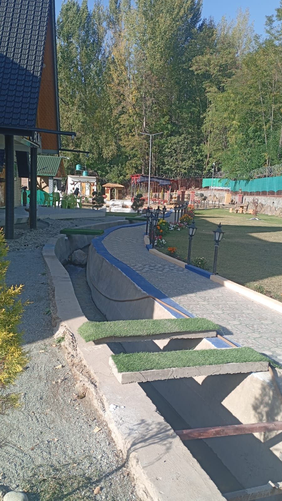 A landscaped area with a curved pathway, seating areas, and a small water feature.