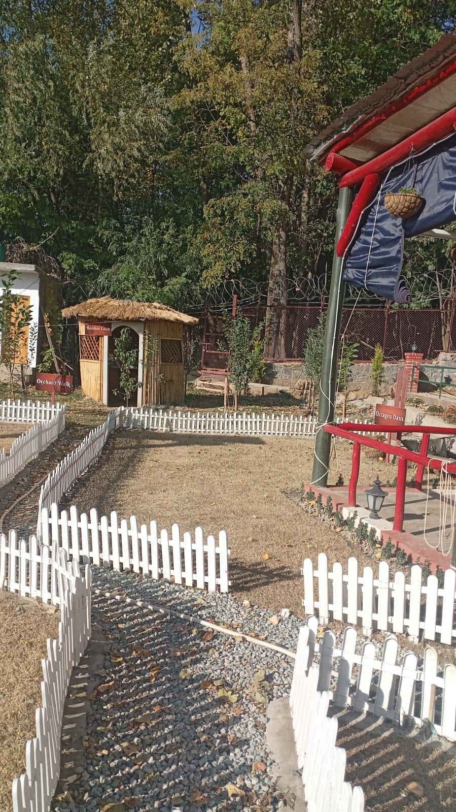 A fenced outdoor area with a small wooden structure, possibly a shelter or kiosk, and a white picket fence.