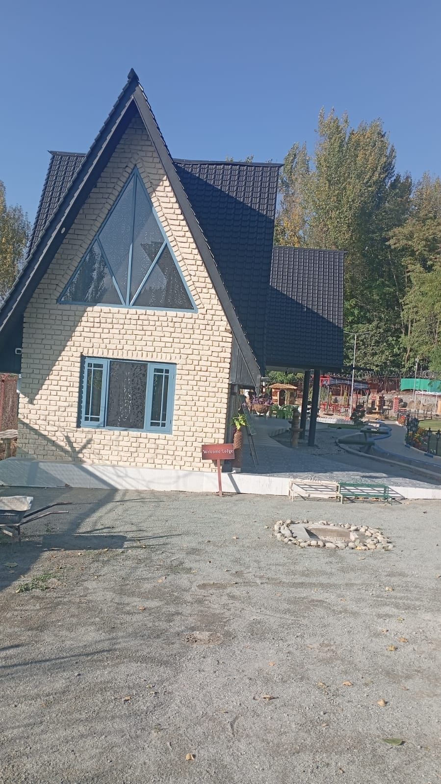 A lodge with a triangular roof, a brick facade, and a sign reading 'Welcome Lodge.'