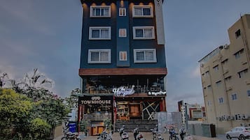 A multi-story building with a sign reading 'OYO TOWNHOUSE' and a restaurant named 'The Hangout' on the ground floor.