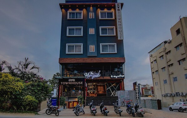 A multi-story building with a sign reading 'OYO TOWNHOUSE' and a restaurant named 'The Hangout' on the ground floor.