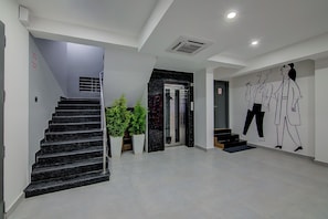 Decoração moderna com escadaria, sala de estar e uma parede com obra de arte minimalista.