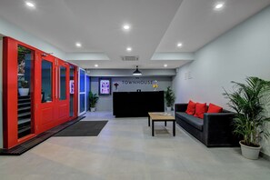 Interior moderno com balcão de recepção, armário vermelho, sofá com almofadas vermelhas e planta em vaso.