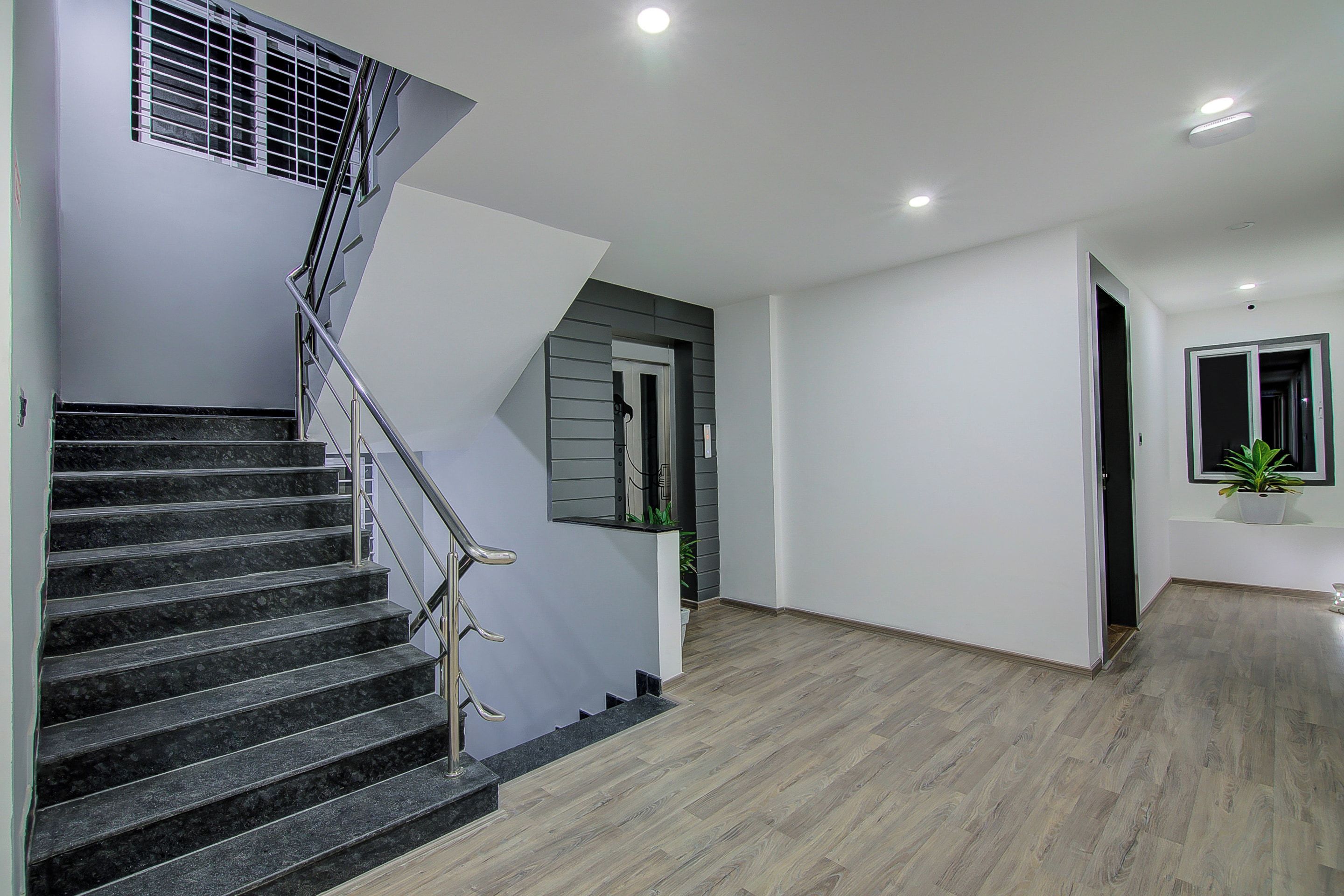 Un interior moderno con una escalera, un pasillo y una puerta que da a otra habitación.
