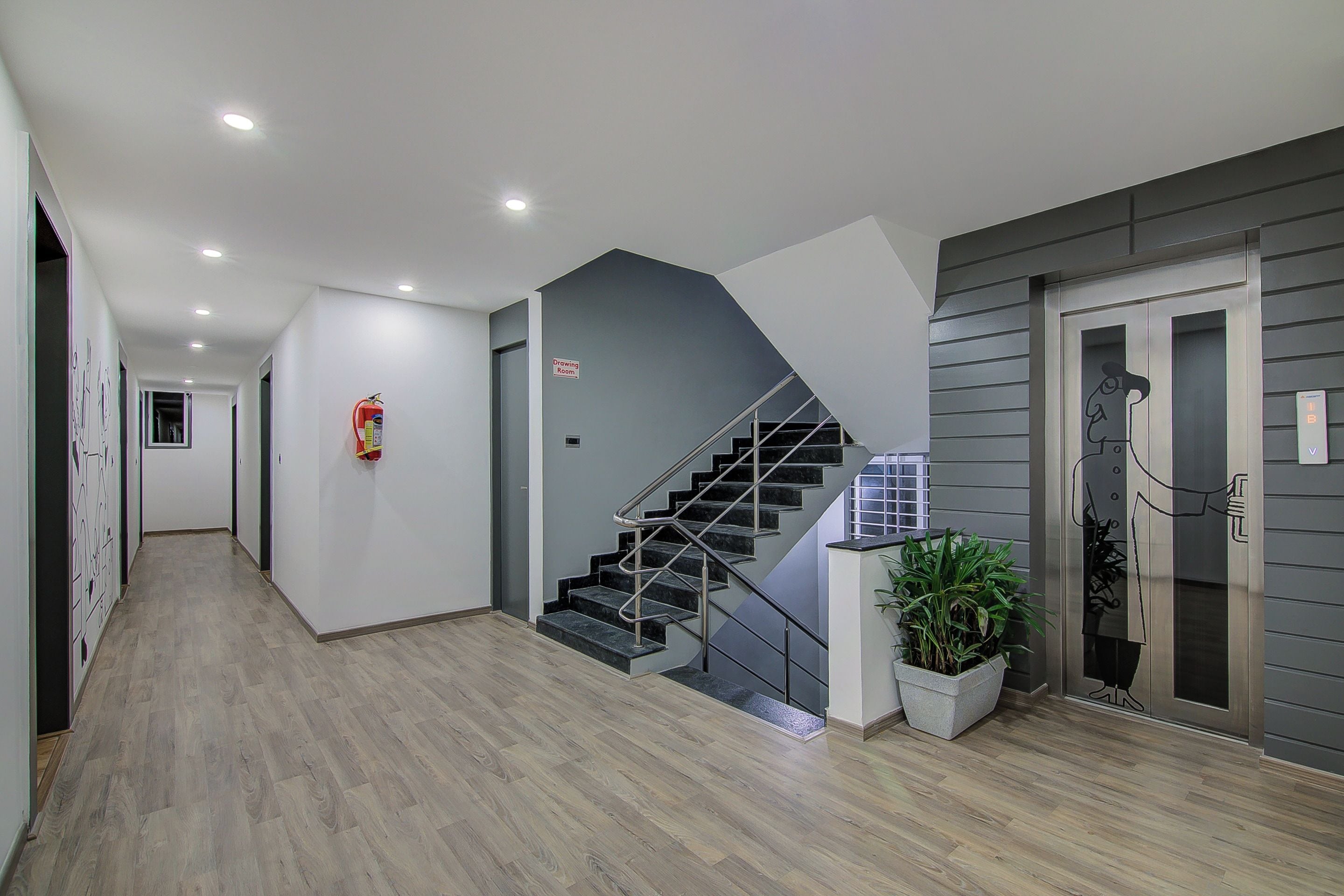 A modern interior with a wooden floor, a staircase, and a fire extinguisher.