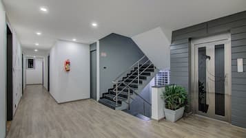 A modern interior with a wooden floor, a staircase, and a fire extinguisher.