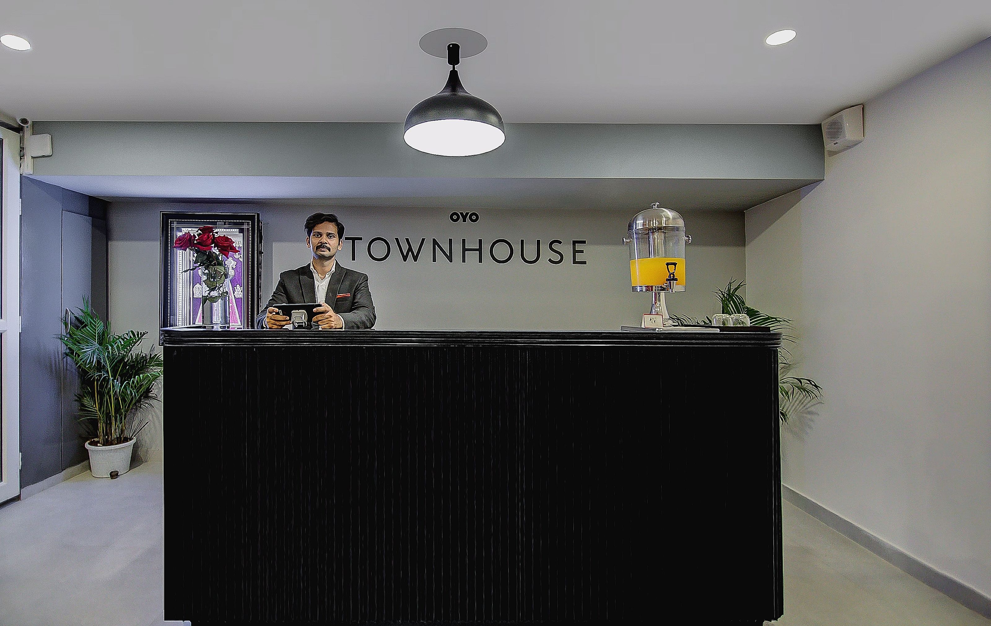 Un mostrador de recepción con un cartel que dice 'TOWNHOUSE' y una cafetera a la derecha.