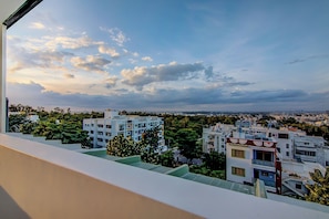 A residential area with multi-story buildings, a clear sky with clouds, and a distant view of a cityscape. - Townhouse Global Village Tech Park (Bangalore)