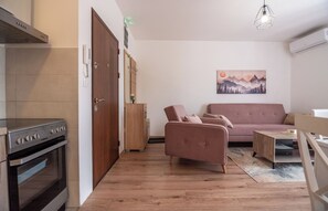 A compact living space with a kitchenette, a sofa, a dining table, and a painting on the wall. - Zabljak Hills City Center-only 400m walking distance from the center (Žabljak)