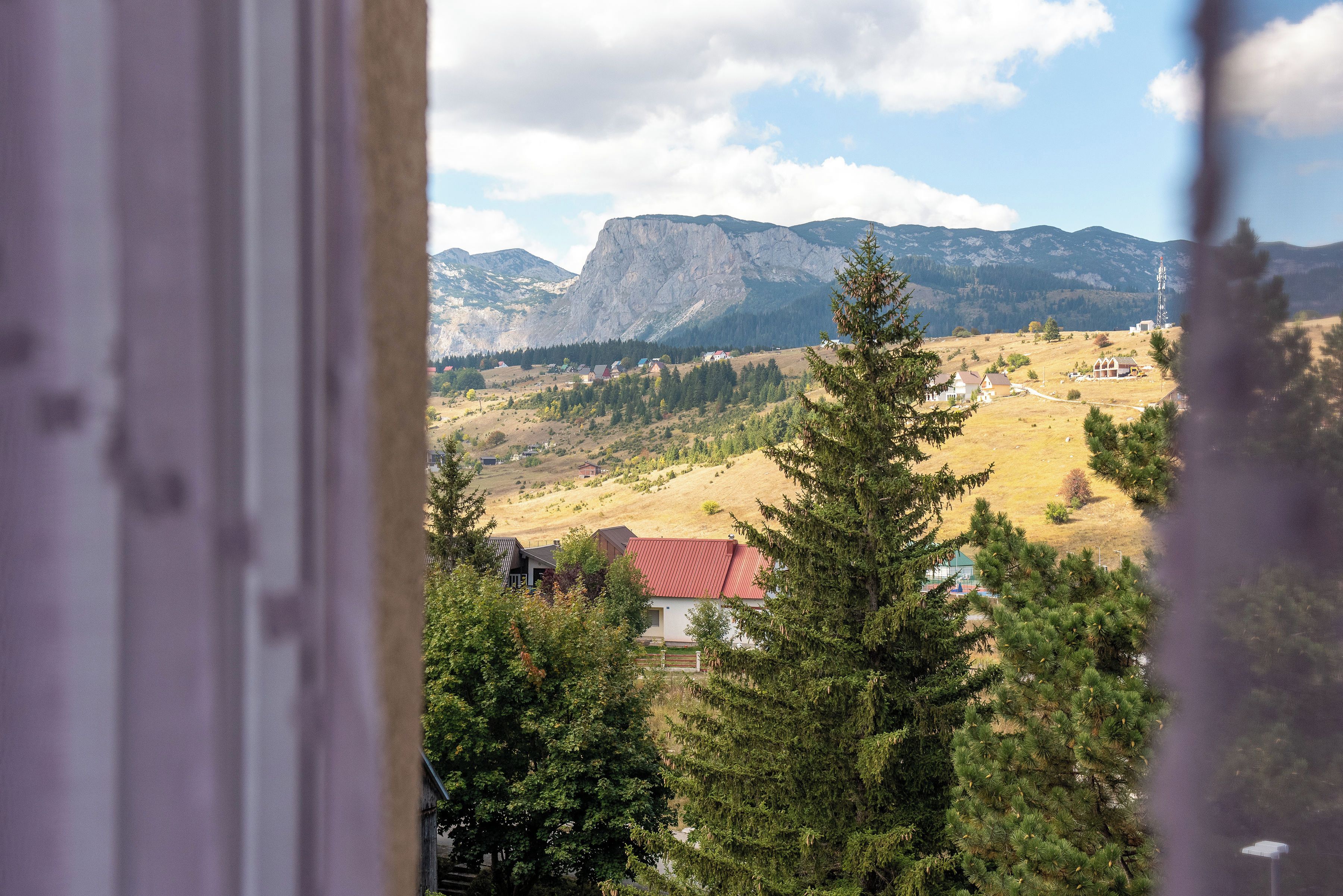 A mountainous landscape with houses and a prominent rocky peak.