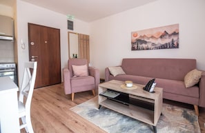 Una sala de estar con un sofá, una silla, una mesa de centro y un cuadro en la pared.