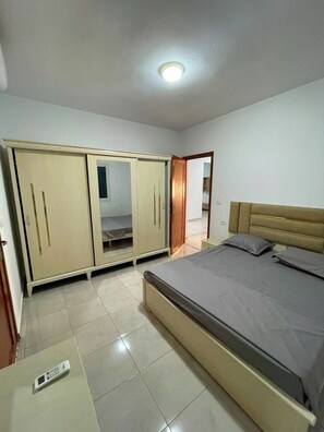 Ein Schlafzimmer mit einem Bett, einem Kleiderschrank und einem digitalen Thermometer auf dem Boden.