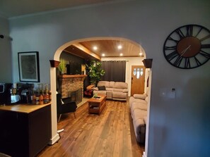 A living room with a fireplace, a sofa, a coffee table, and a clock on the wall. - Cozy & Stylish Leamington Retreat / Fireplace, Modern Comfort & Prime Location (Leamington)