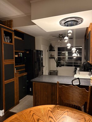A kitchen with a central island, dark cabinetry, and a ceiling fan. - Cozy & Stylish Leamington Retreat / Fireplace, Modern Comfort & Prime Location (Leamington)