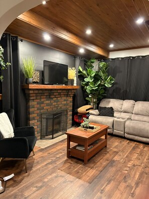 A modern living room with a fireplace, a sofa, a coffee table, and a television. - Cozy & Stylish Leamington Retreat / Fireplace, Modern Comfort & Prime Location (Leamington)