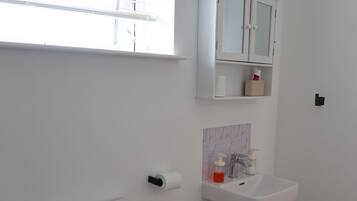 Ein modernes Badezimmer mit Toilette, Waschbecken, einem Schrank und einem Fenster.