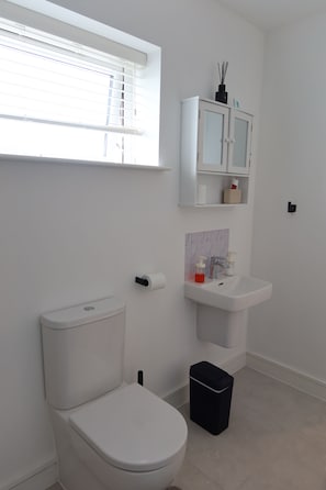 Un baño moderno con inodoro, lavamanos, armario y ventana.