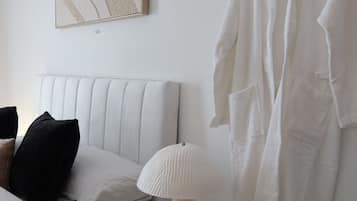 Una camera da letto con un letto, un comodino con una lampada, un appendiabiti e un quadro astratto appeso al muro.