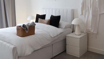 Una camera da letto moderna con un letto grande, un comodino, una lampada, un appendiabiti e un'opera d'arte a parete.