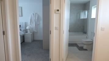 A modern bathroom with a bathtub, toilet, and shower.
