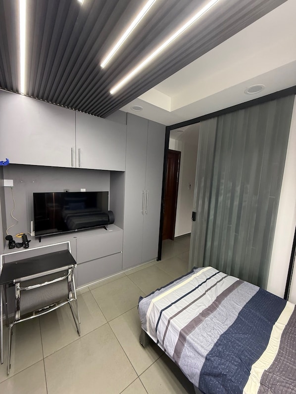 Ein modernes Schlafzimmer mit einem Bett, einem Schreibtisch und einem Fernseher.