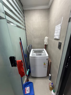 Ein kleiner Hauswirtschaftsraum mit Waschmaschine, Mopp und Reinigungsmitteln.