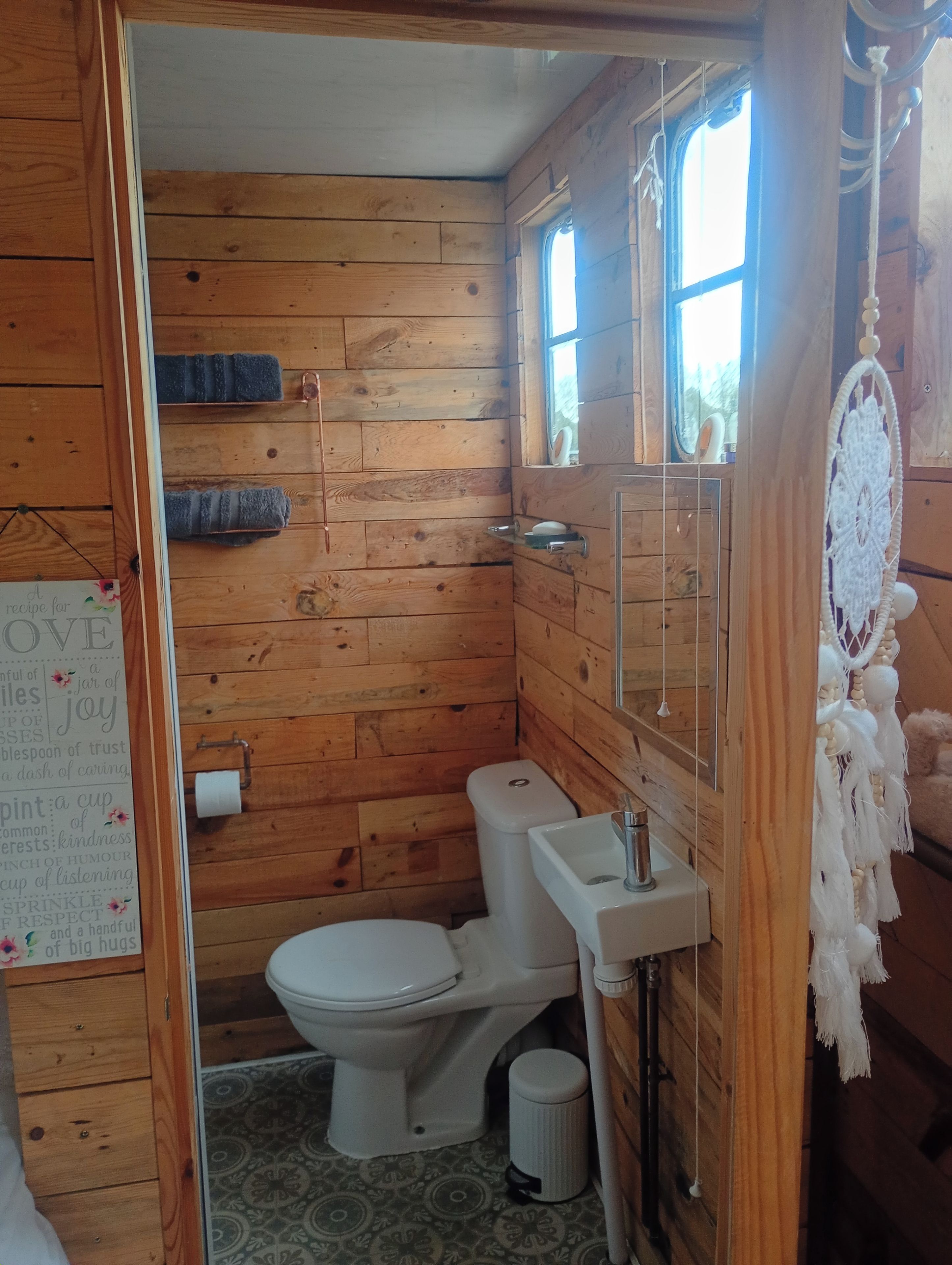 Une salle de bain en bois avec des toilettes, un lavabo et une fenêtre.