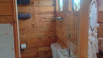 Une salle de bain en bois avec des toilettes, un lavabo et une fenêtre.
