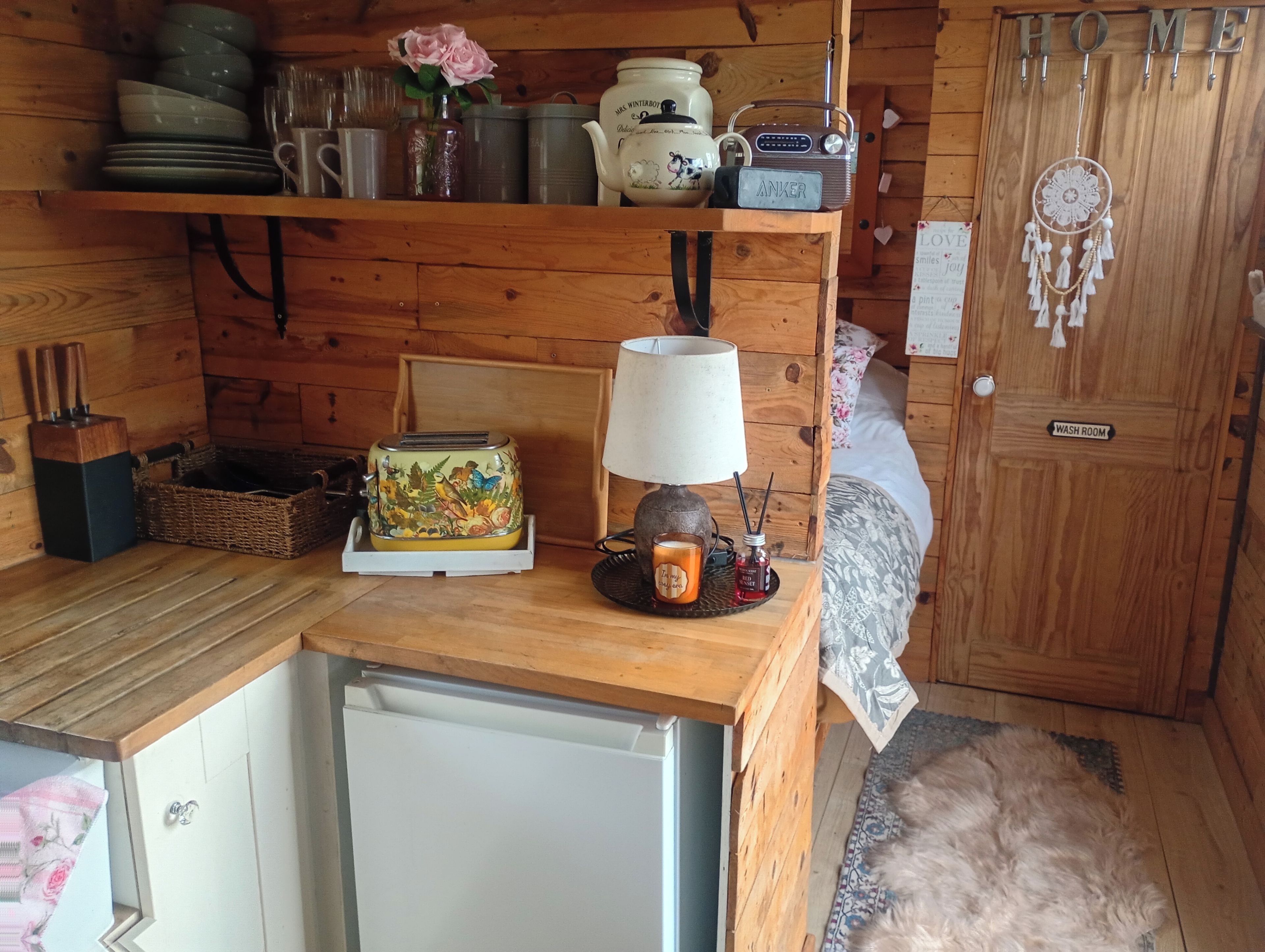 Interior acogedor de una cabaña con revestimiento de madera, un refrigerador, un tostador, una lámpara y un radio.