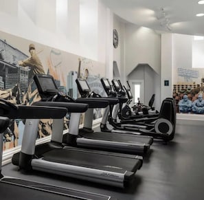 A gym with treadmills, stationary bikes, and weights.