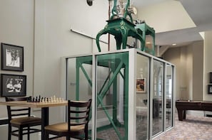 Ein Zimmer mit einem Billardtisch, einem Schachbrett und einer grünen, mechanischen Vorrichtung.