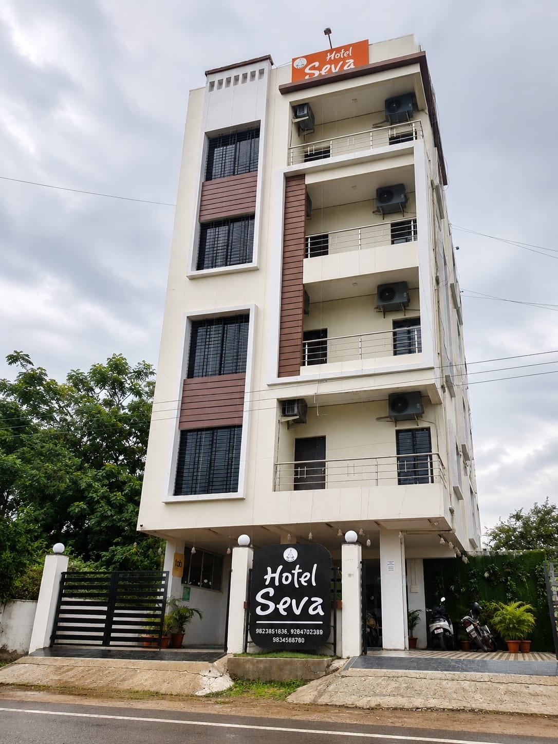 Un immeuble d’hôtel à plusieurs étages, avec une enseigne indiquant « Hôtel Seva » à l’entrée.