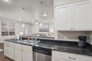 A modern kitchen with white cabinets, a black countertop, and a dishwasher. - Six Gun's Up - 3BR/3BA - Walk to Tech (Lubbock)
