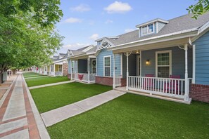 A row of townhouses with front porches, neatly trimmed lawns, and a clear sky. - Six Gun's Up - 3BR/3BA - Walk to Tech (Lubbock)