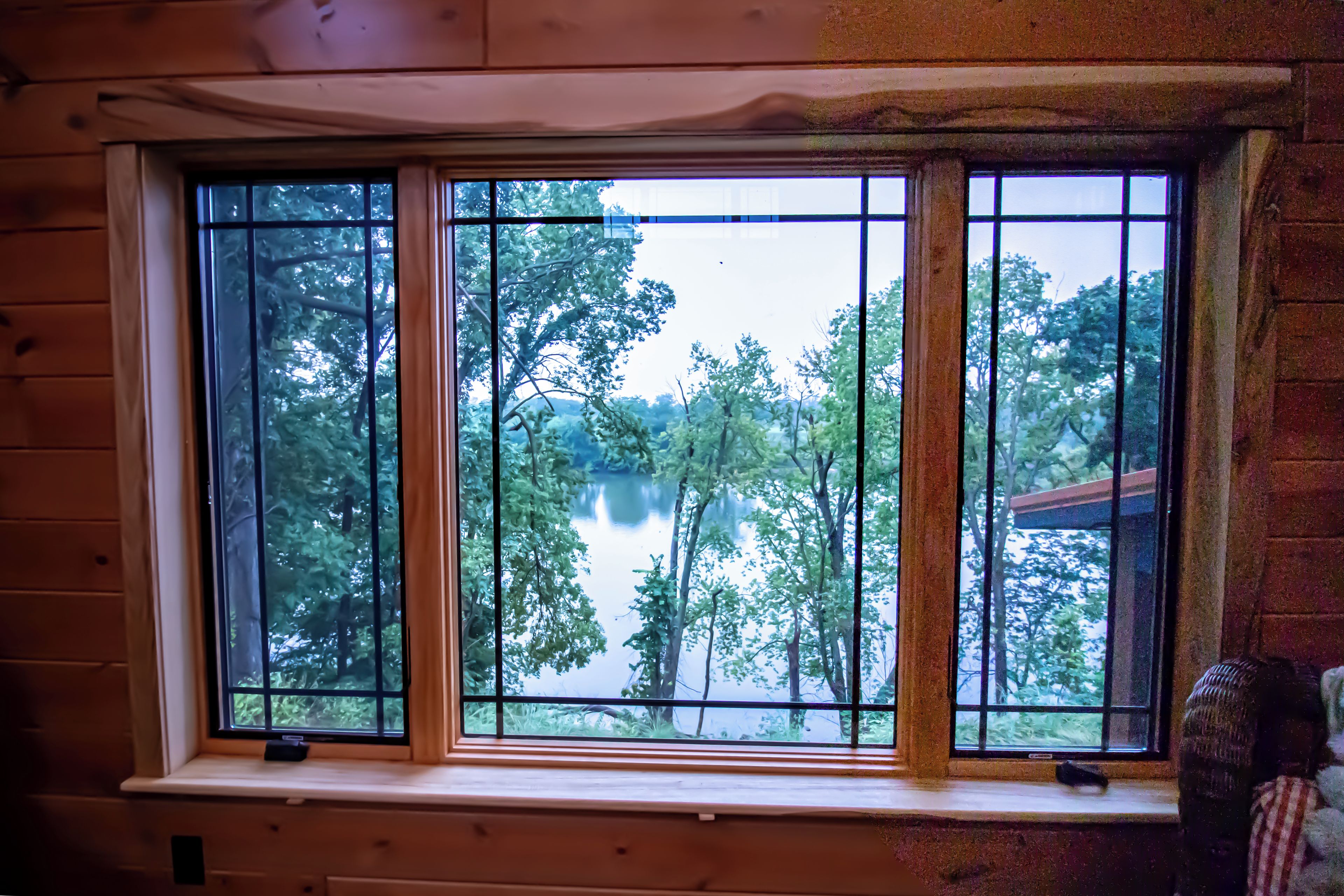 Una ventana con vista a un lago rodeado de árboles.