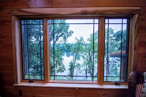 A window with a view of a lake surrounded by trees.